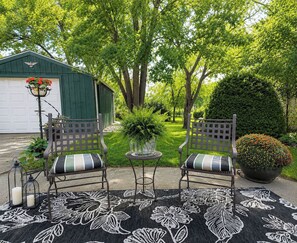 A patio with two chairs, a table, and a potted plant. - King Bed • Vintage Urban Oasis • Near MKE Airport (Milwaukee)