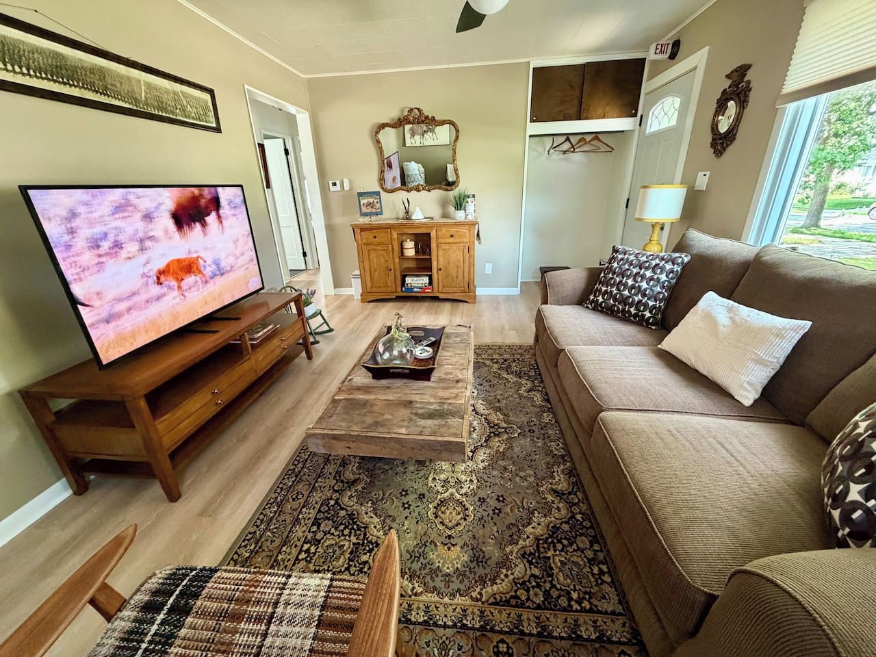 Una sala de estar con televisor, sofá, mesa de centro y una alfombra estampada.