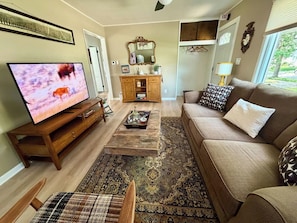 A living room with a television, sofa, coffee table, and a patterned rug. - King Bed • Vintage Urban Oasis • Near MKE Airport (Milwaukee)