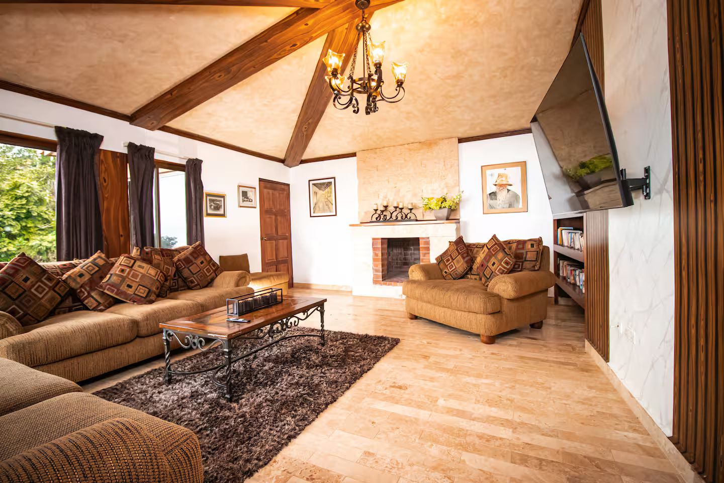 Ein geräumiges Wohnzimmer mit Kamin, zwei Sofas, einem Couchtisch und einer Chandelier.