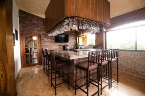 A kitchen with a bar area, a television, and a large window. - La Villa Real — Tu sueño en Boquete.
La Villa Real — Your dream in Boquete. (Jaramillo)