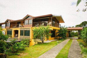 A two-story house with a balcony, a covered porch, and a paved walkway. - La Villa Real — Tu sueño en Boquete.
La Villa Real — Your dream in Boquete. (Jaramillo)