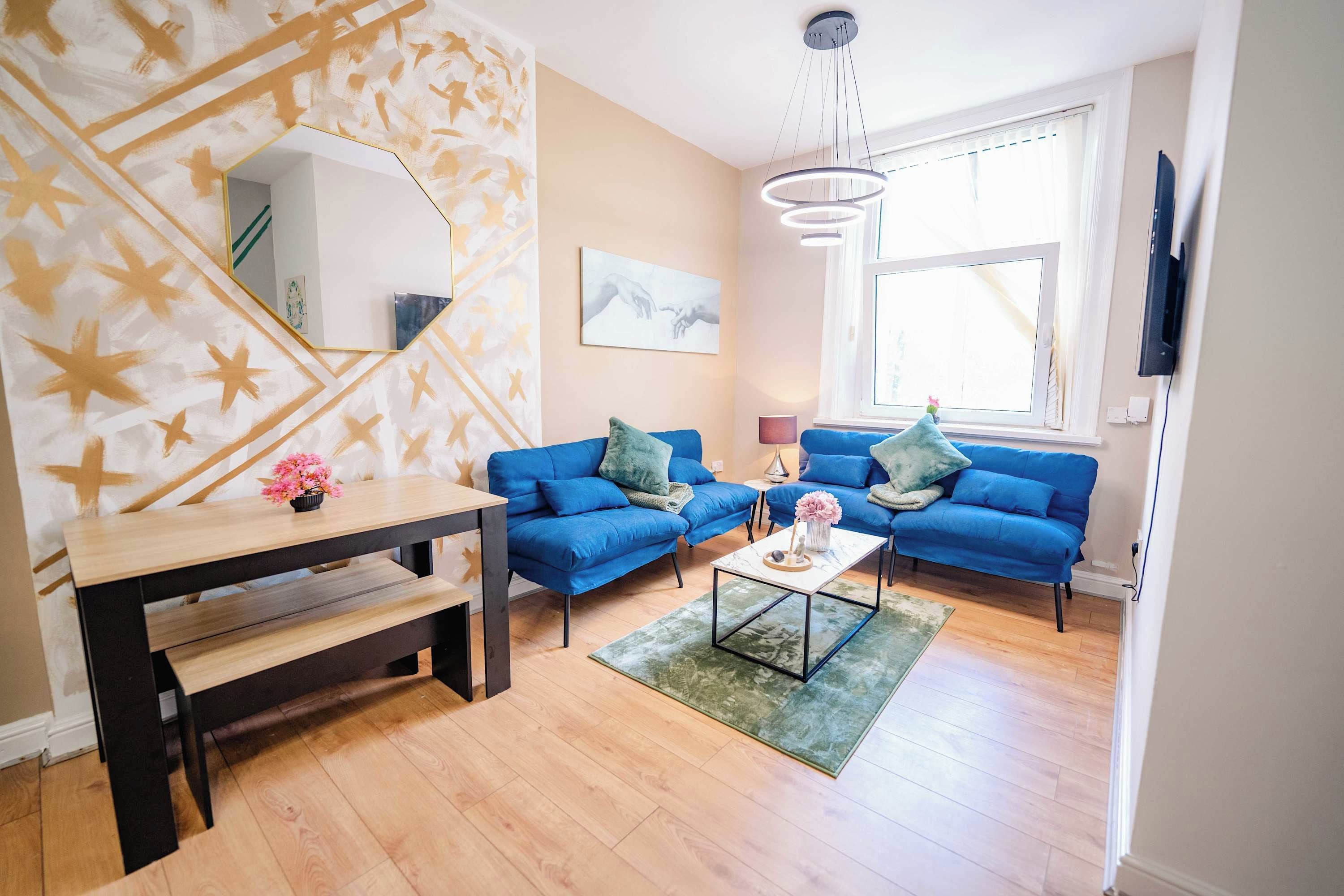Un salon moderne avec un canapé bleu, une table basse en bois et un grand miroir accroché au mur.