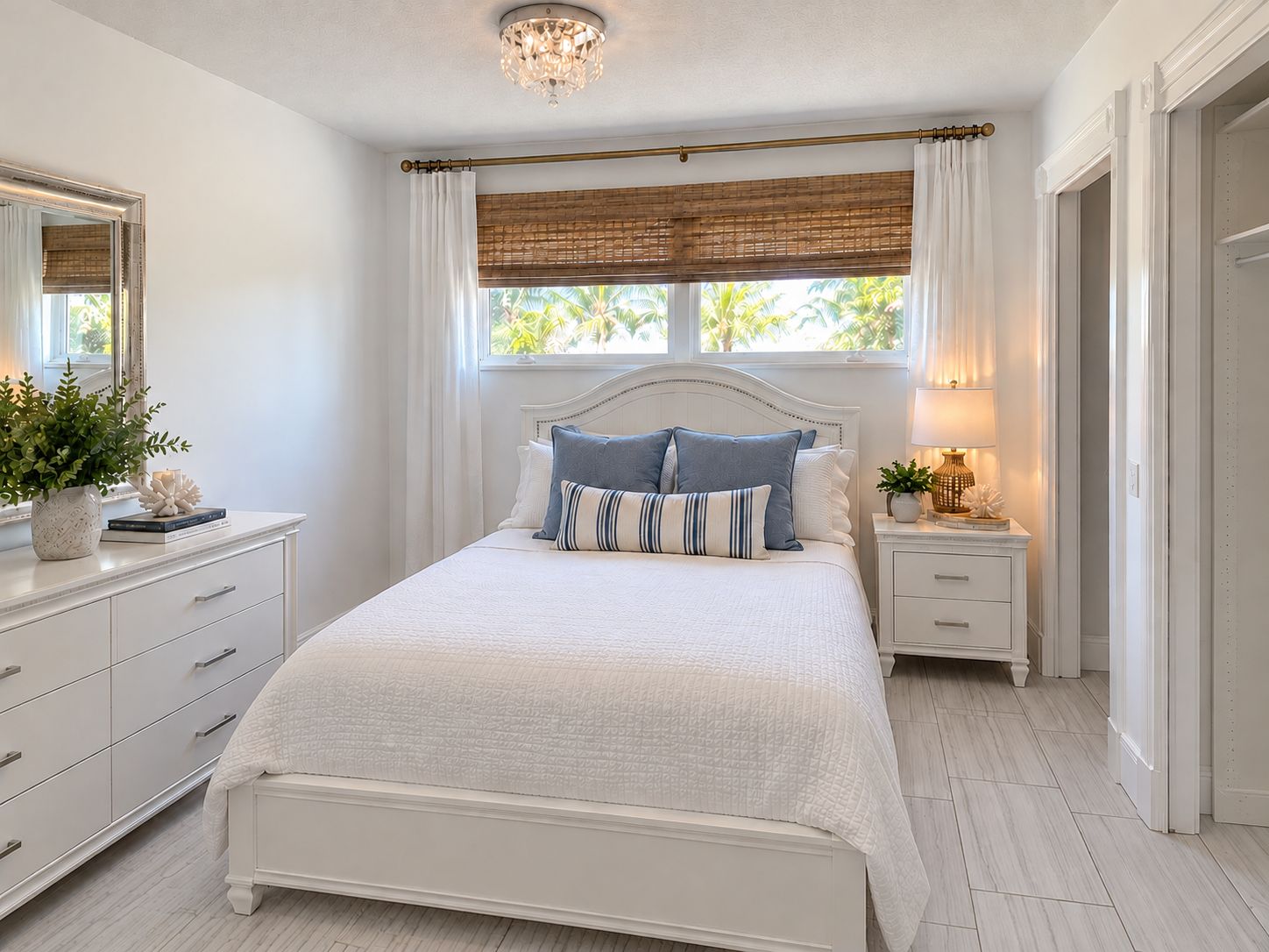 A bedroom with a bed, bedside tables, a mirror, and a window with curtains.
