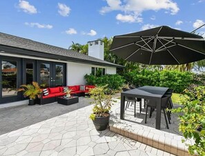 Eine moderne Außenpatio mit Essbereich, einem roten Sofa und einem großen Sonnenschirm.