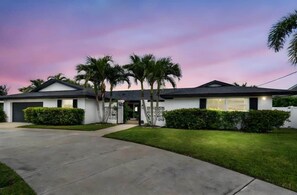 A two-story house with a driveway, palm trees, and a well-maintained lawn. - Belleair Beach Waterfront Residence (Belleair Beach)