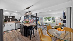 A modern kitchen with white cabinets, a black backsplash, and a colorful floral mural. - Gather at 104 - Walk to Downtown Perrysburg (Perrysburg)