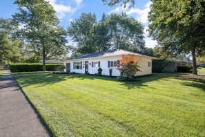Une maison de plain-pied avec une pelouse bien entretenue et une allée menant à la porte d’entrée.