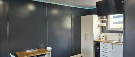 Cocina compacta con comedor, que incluye armarios, un lavamanos y un ventanal.