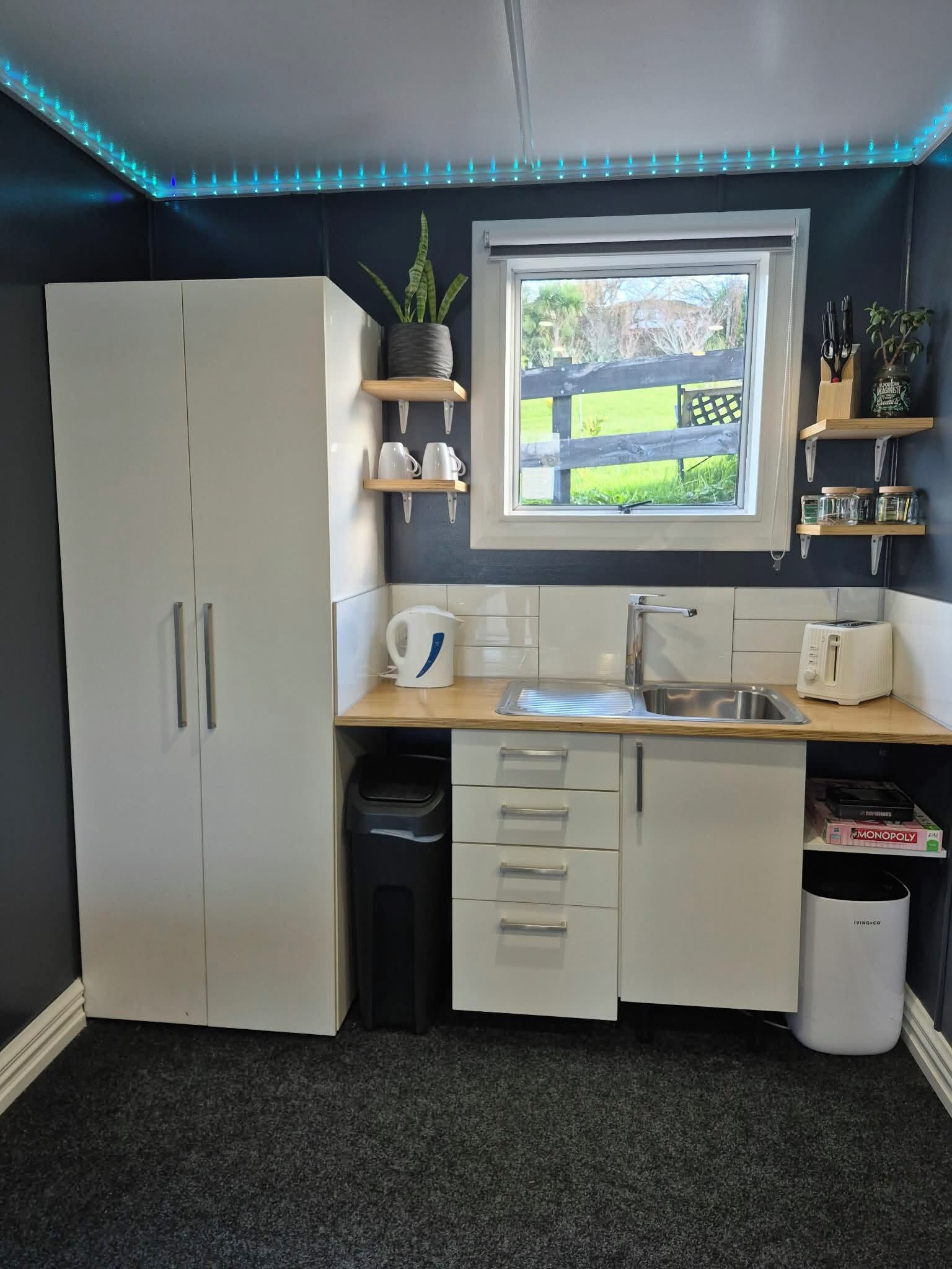 A compact kitchen with a window, white cabinets, a sink, and a toaster.