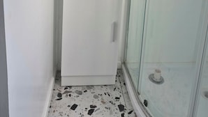 Un baño con ducha, lavamanos y un cuadro en la pared.