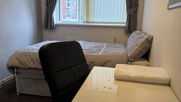 A bedroom with a bed, a desk, and a chair.