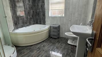 A modern bathroom with a bathtub, toilet, and sink.