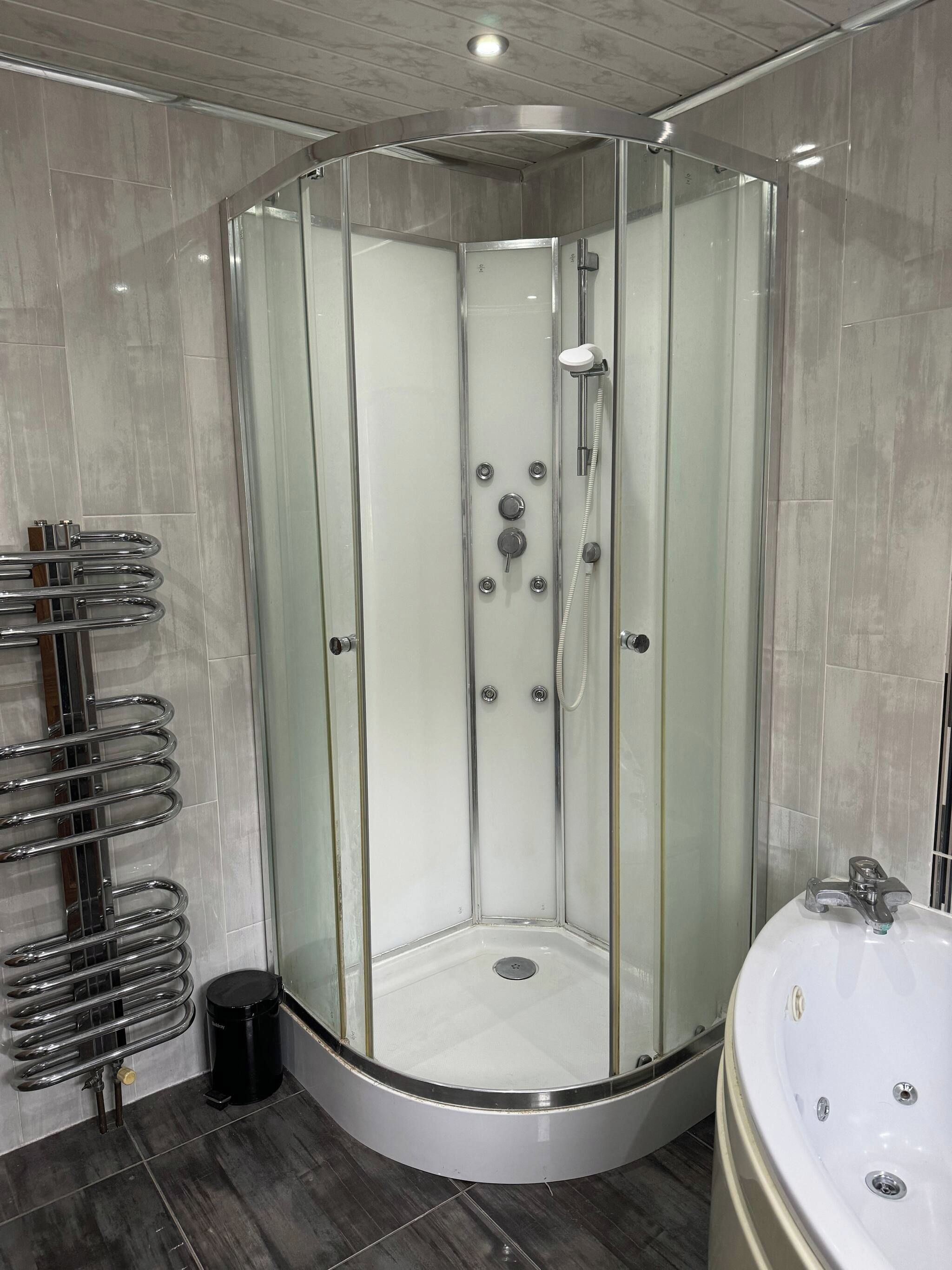 A modern shower enclosure with a glass door, a built-in seat, and a handheld showerhead.