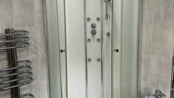 A modern shower enclosure with a glass door, a built-in seat, and a handheld showerhead.