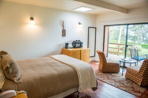 A bedroom with a bed, a wooden dresser, a chair, and a table. - Sunset Room at Buckhorn Cove near Mendocino w/ Ocean View, Dog-Friendly, EV Chgr (Mendocino County)