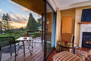 Un balcón con mesa y sillas, chimenea y televisor.