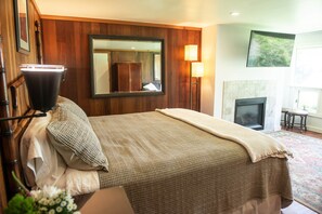 Ein Hotelzimmer mit Bett, Spiegel, Lampe, Kamin und Fenster.