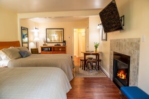 A hotel room with a bed, a desk, a chair, a fireplace, and a mirror. - Forest Den at Buckhorn Cove near Mendocino - cozy gas fireplace & sleeps 4 (Mendocino County)