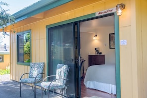 A motel room with a bed, two chairs, a desk with a lamp, and a window. - Meadow Room at Buckhorn Cove near Mendocino - Cozy Gas Fireplace & EV Charger (Mendocino County)