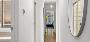 A hallway with a door on the left, a light fixture in the center, and a curved mirror on the right. - Mia’s Place: Modern Pet-Friendly Geelong West Stay (Greater Geelong)