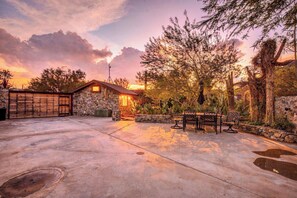 A stone building with a wooden door, surrounded by a paved area and cacti. - Desert Retreat | Hot Tub & Mountain Views (Tucson)