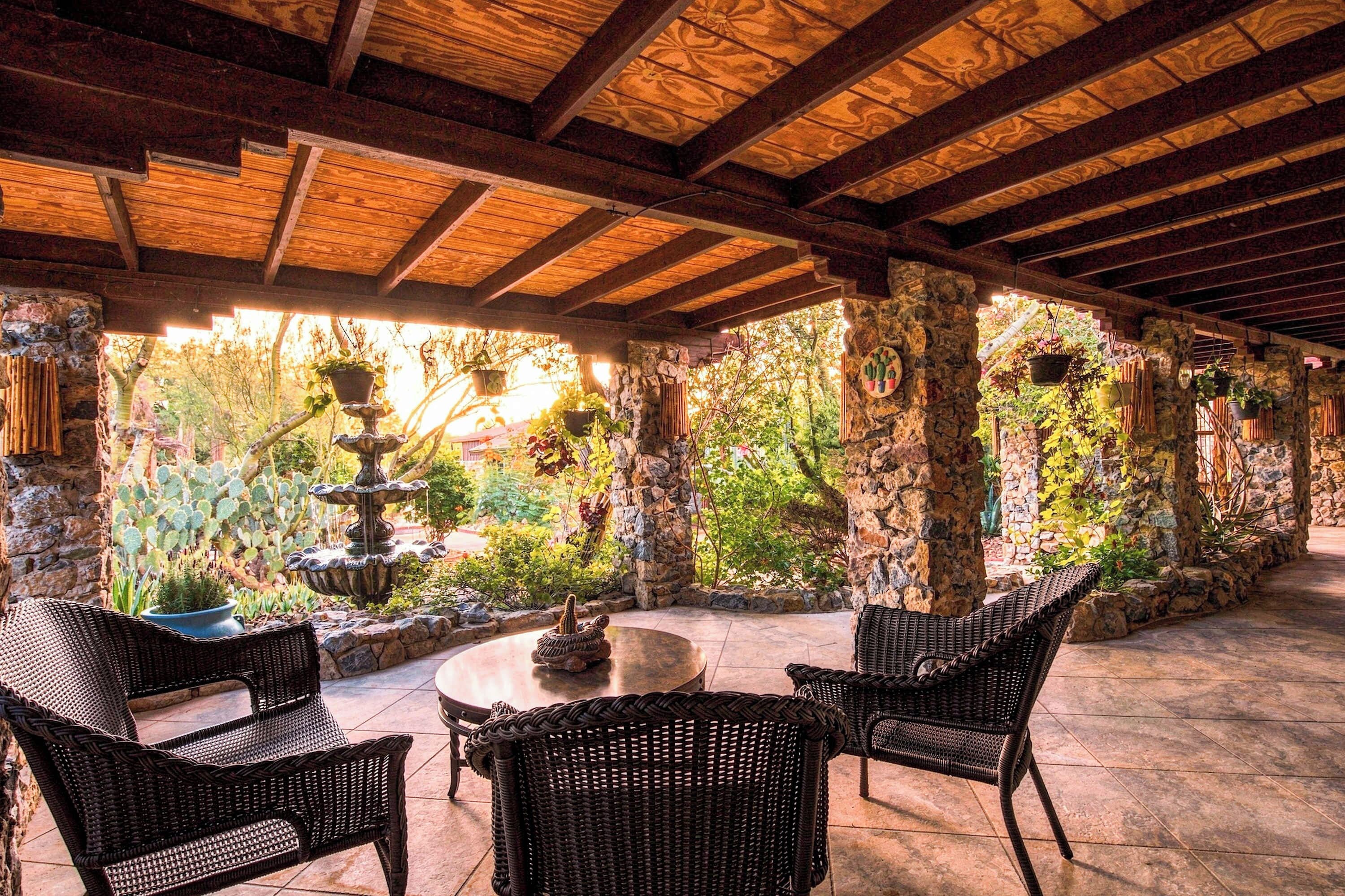 An outdoor patio area with stone pillars, wicker furniture, and a central table.