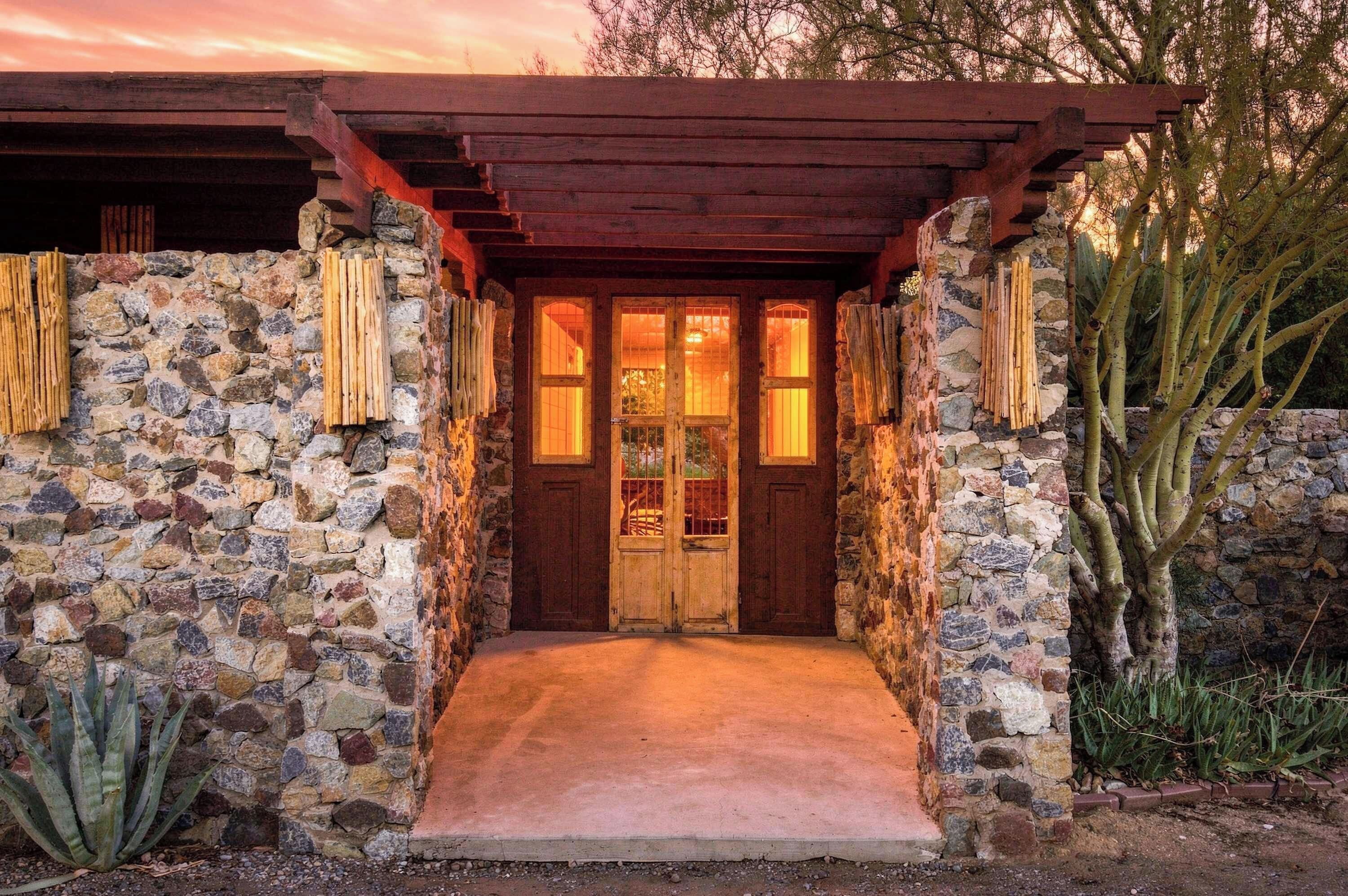 A stone house with a wooden door and a concrete entrance.