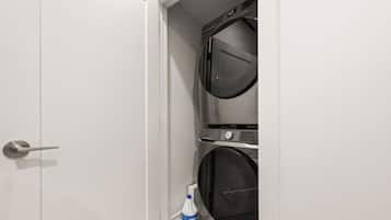 A closed door with a metallic handle, a washing machine, and a bottle of detergent on the floor.