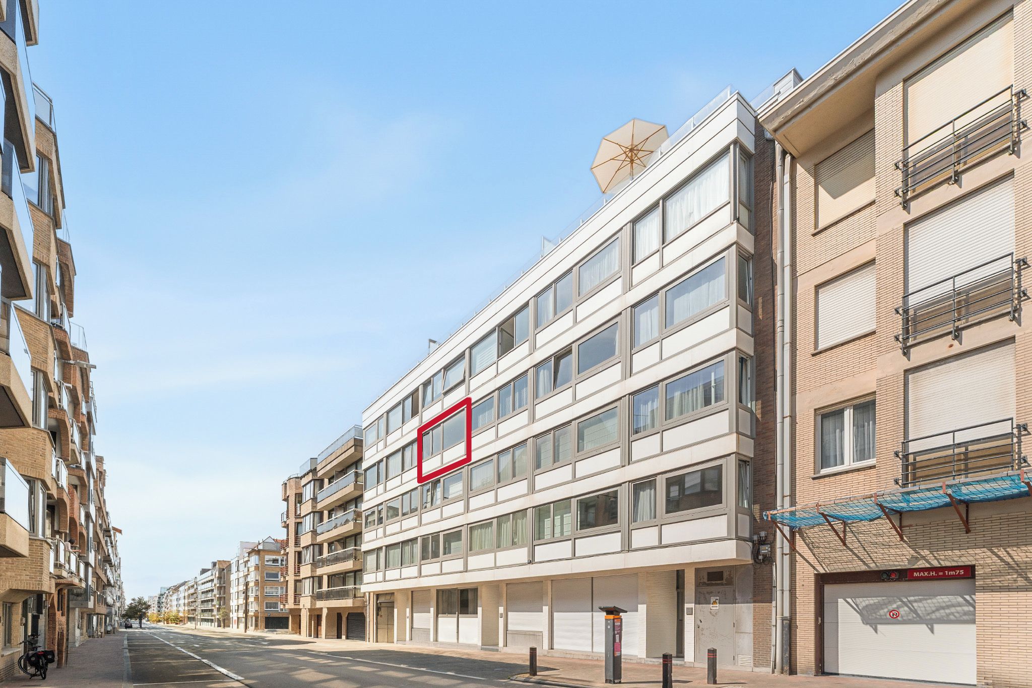 A multi-story building with a flat facade, large windows, and a clear sky.