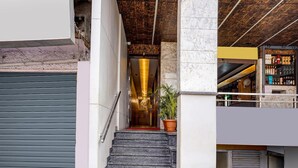A staircase leading to a lobby with a potted plant, a closed shutter door, and a bar area with shelves. - Deluxe With Twin Bed Hotel Metro Park (Bengaluru)