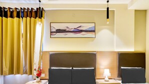 A hotel room with a large bed, two bedside tables, a nightstand with a lamp, a painting on the wall, and a window with curtains. - Deluxe With Twin Bed Hotel Metro Park (Bengaluru)