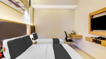 Hotellihuone, jossa on kaksi sänkyä, työpöytä, tuoli, televisio ja kattotuuletin.