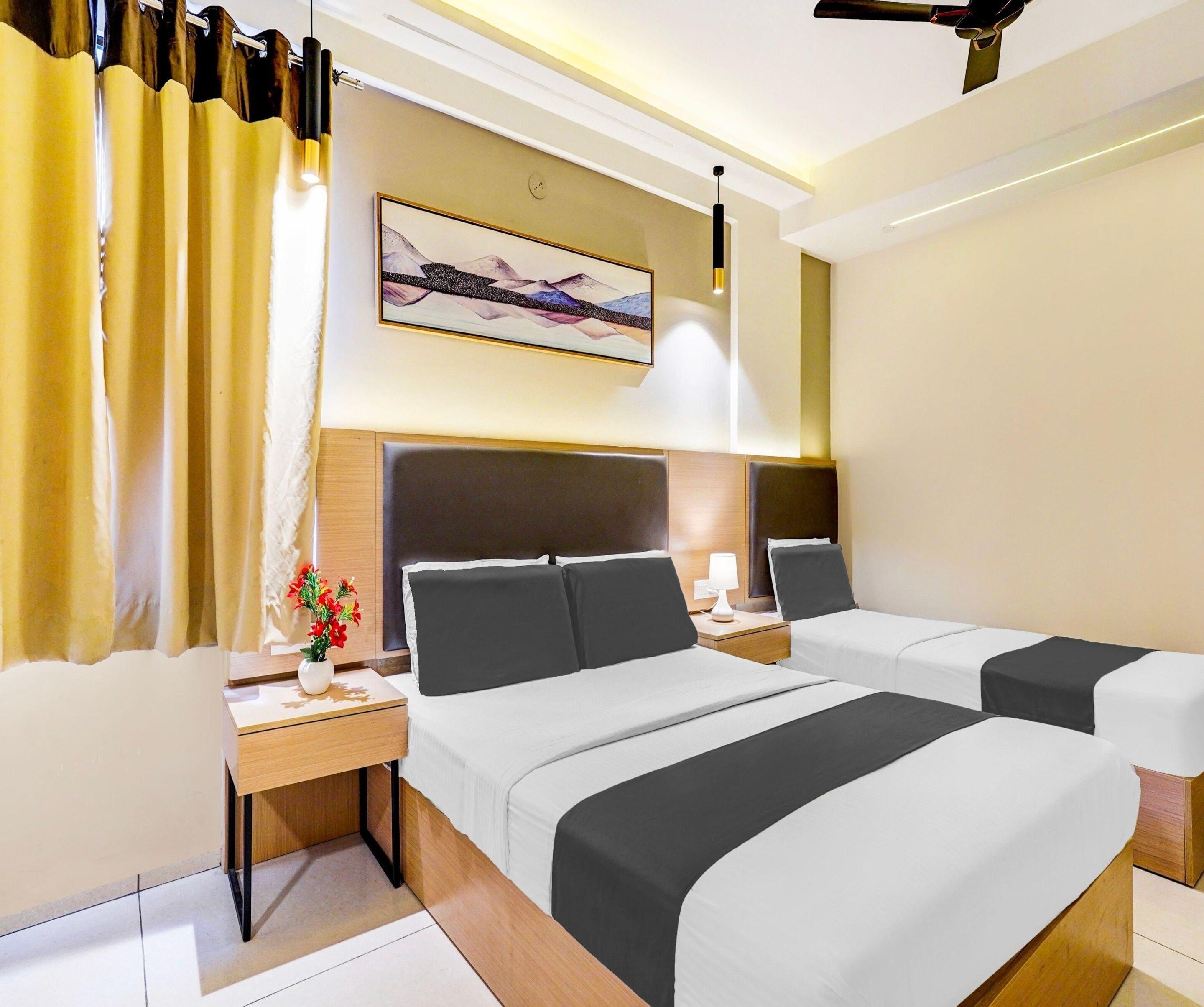 Habitación de hotel con dos camas, una mesita de noche con lámpara, un cuadro en la pared y una ventana con cortinas.