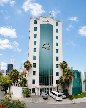 A high-rise hotel with a prominent glass facade, multiple balconies, and a clear sky.