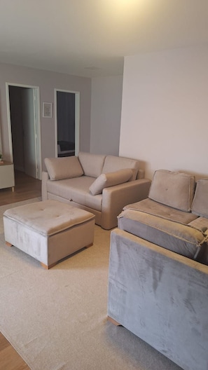 A living room with a beige sofa, a matching ottoman, and a grey armchair. - New apartment in Santa Teresa-ES, enclosed balcony with mountain views. (Santa Teresa)