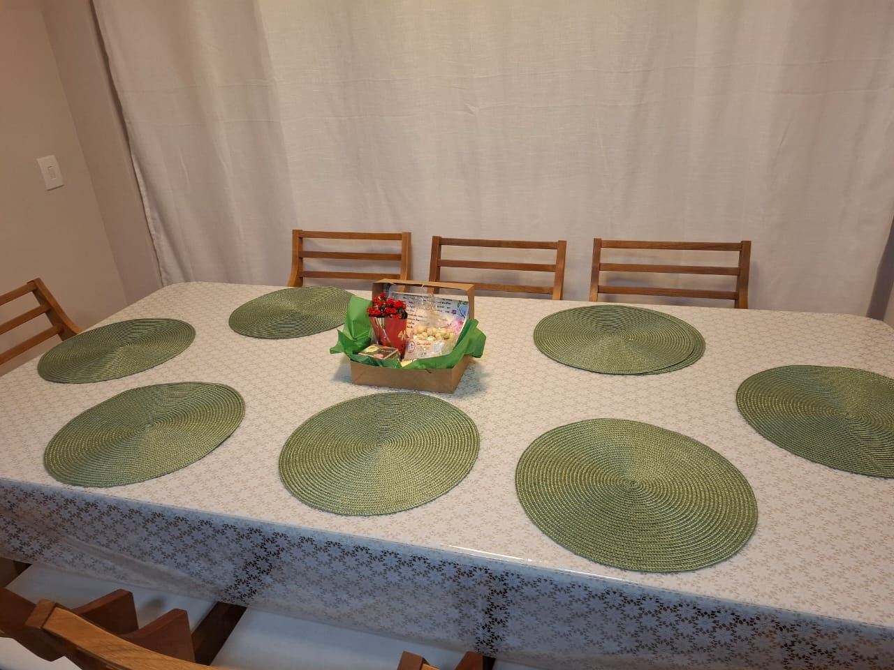 A dining table with a white tablecloth and green placemats, surrounded by wooden chairs.