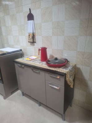 A kitchenette with a stove, a red kettle, and a patterned tablecloth. - New apartment in Santa Teresa-ES, enclosed balcony with mountain views. (Santa Teresa)