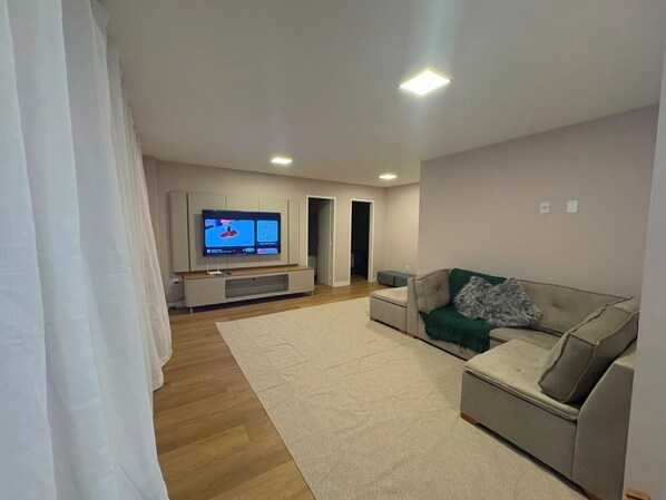 Un saló amb televisió de pantalla plana, un sofà, una taula de centre i una catifa.