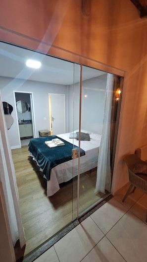 A bedroom with a bed, a mirror, and a door leading to another room. - New apartment in Santa Teresa-ES, enclosed balcony with mountain views. (Santa Teresa)