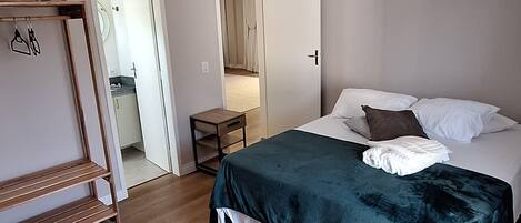 Un dormitorio con cama, mesita de noche, armario y espejo.