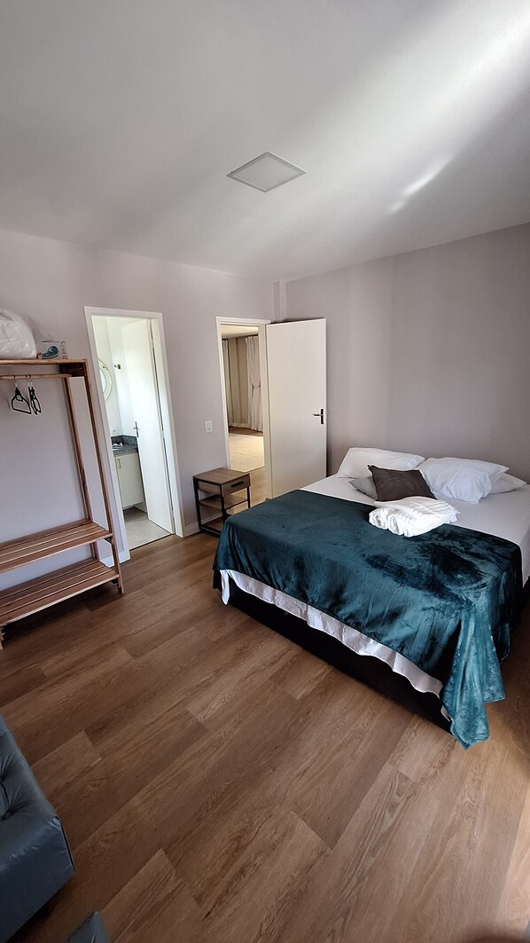 A bedroom with a bed, a bedside table, a wardrobe, and a mirror.