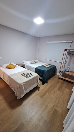 Habitació amb dos llits individuals, una taula petita, una pissarra i un terra de fusta.