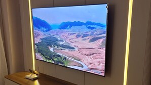 Televisão de tela plana presa na parede com um armário de madeira embaixo.