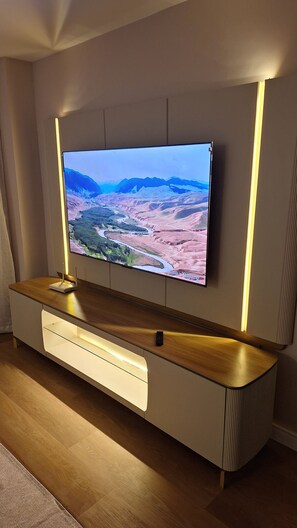 A flat-screen TV mounted on a wall with a wooden cabinet below. - New apartment in Santa Teresa-ES, enclosed balcony with mountain views. (Santa Teresa)