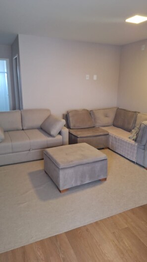 A living room with a beige sofa, a matching ottoman, and a small coffee table.