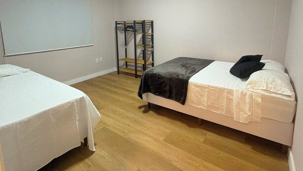 Quarto com duas camas, um quadro branco e piso de madeira.