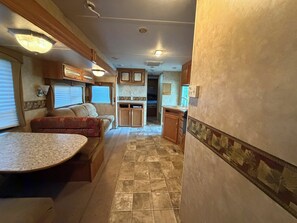 A compact RV interior with a kitchenette, a dining area, and a seating space. - Hidden Lakeside Retreat! Camper + Bunkhouse in Charming Sawyer. (Sawyer)