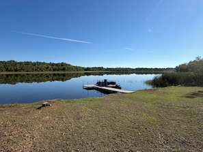 A calm lake with a dock and a boat.