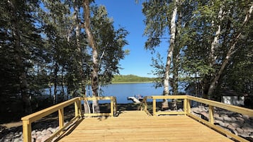 Ett trädäck som leder ner till en sjö, med fri sikt över vattnet och de omgivande träden.